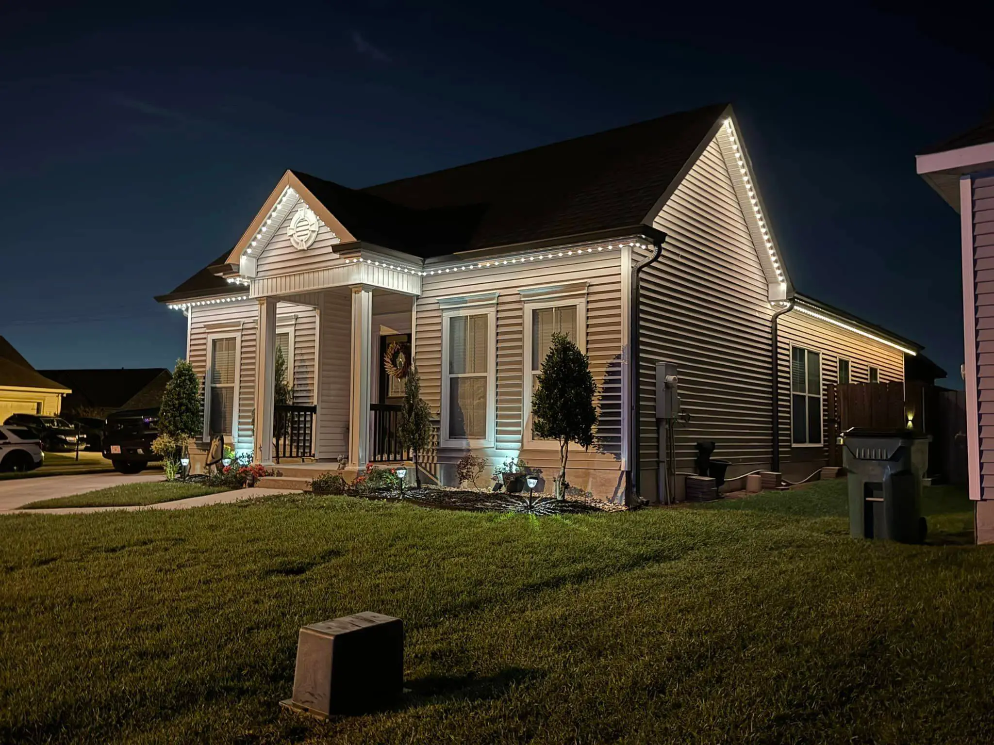 Brick Westbank house at night with white Trimlight on the eaves and warm downlights.
