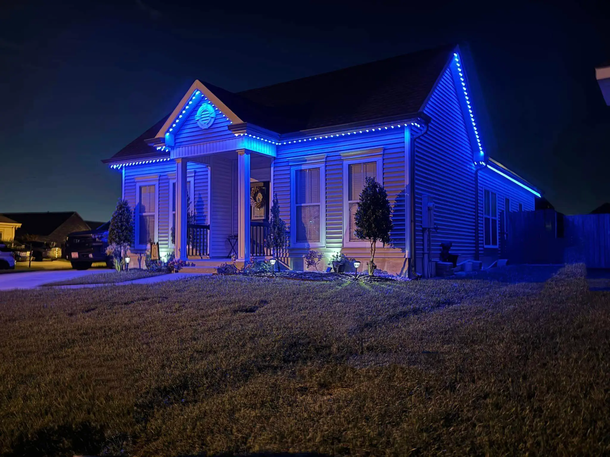 Metal Westbank building with blue Trimlight on the roof and white wall lights.