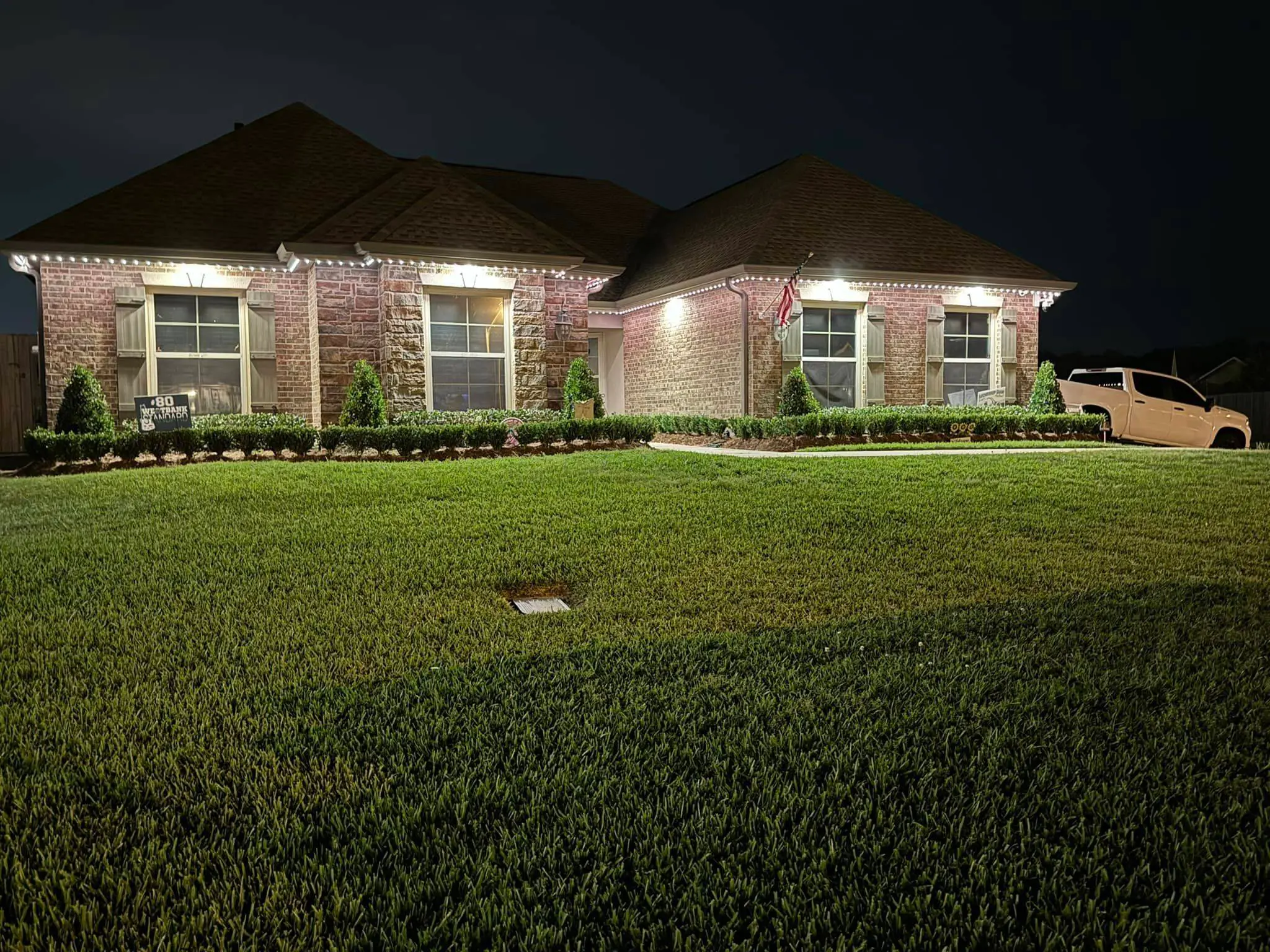 White house at night with warm Trimlight on the porch roof and cool light along the upper eave.