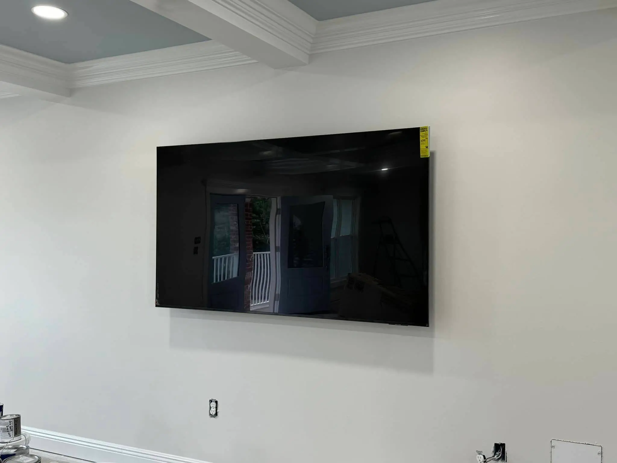 Large wall-mounted television in a room with crown molding, wired for a home theater.